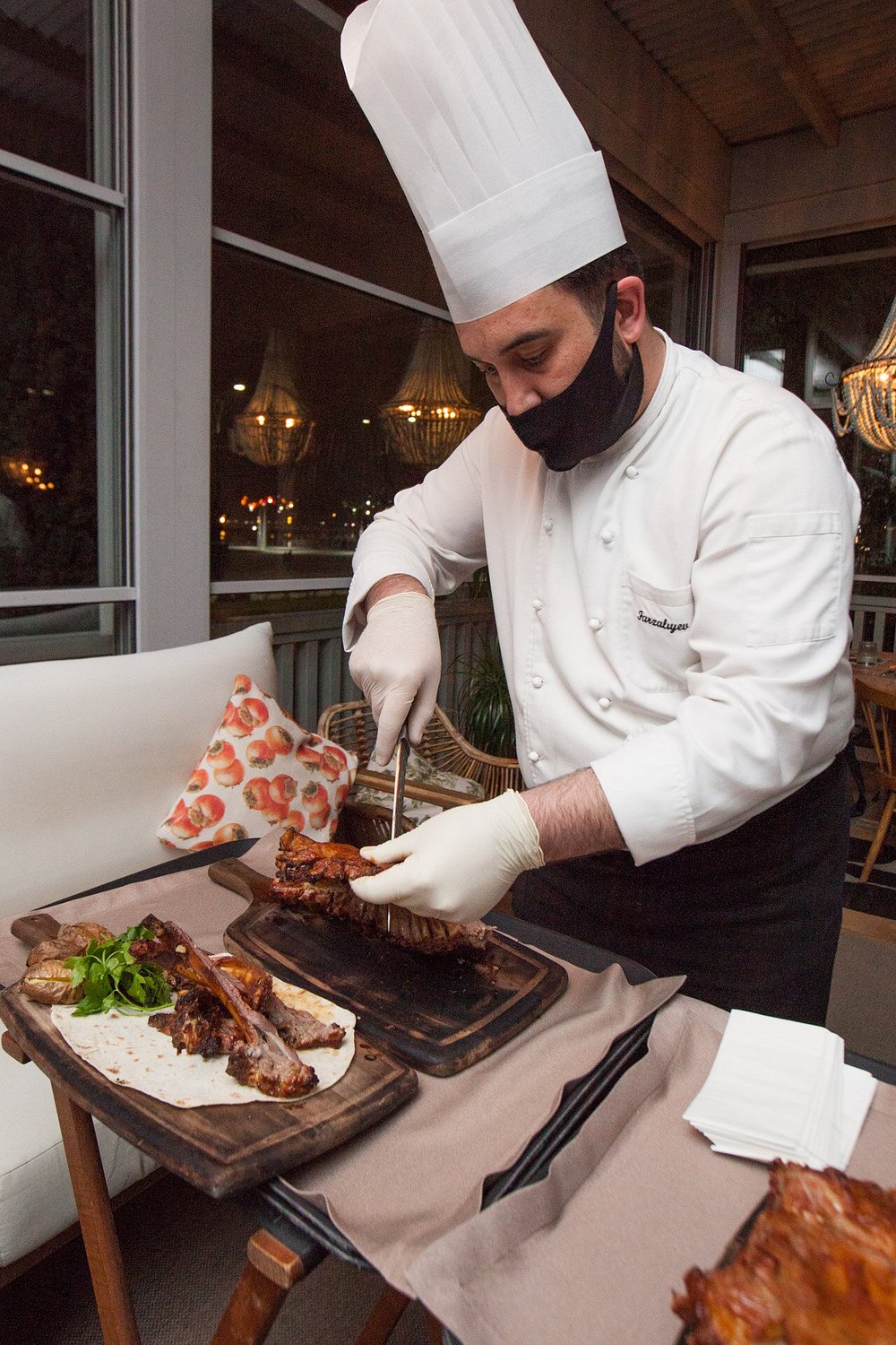A chef carving meat tableside in a candlelit restaurant dining room