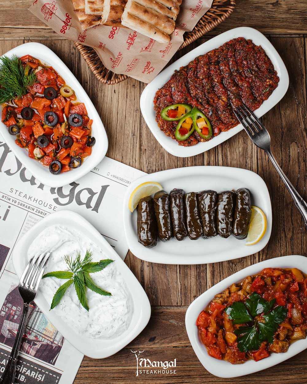 A spread of Azerbaijani mezze with grilled peppers, vine leaves, yoghurt and warm bread at Mangal Steak House in Baku