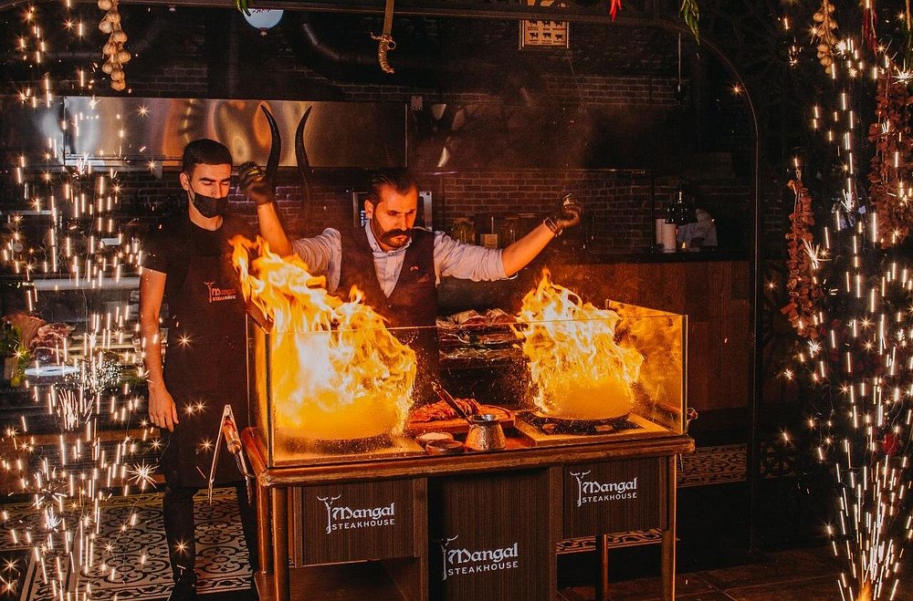 Flames rising from the open grill trolley as the grill master works in front of the guests at Mangal in Baku