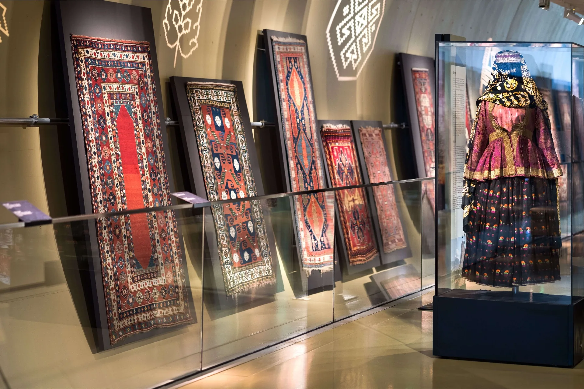 Antique hand-woven Azerbaijani carpets and a traditional embroidered costume on display at the Azerbaijan Carpet Museum in Baku