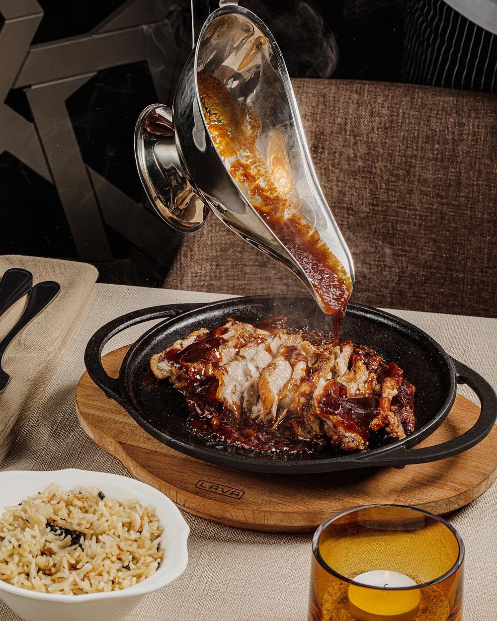Sauce poured over a sizzling cast-iron dish of chicken with herbed rice at Shur Jazz Hall in Baku