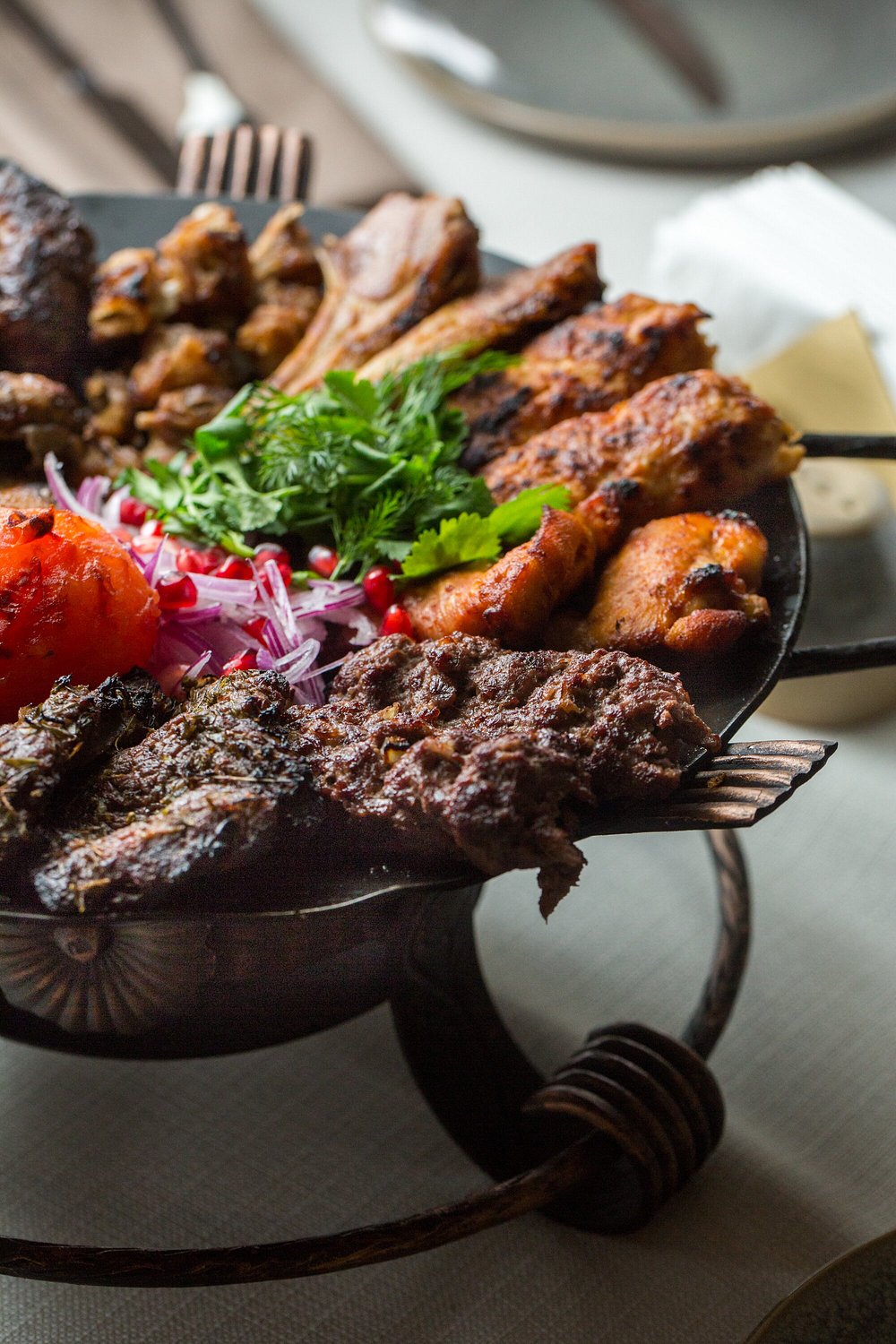 A copper brazier of mixed grilled meats, lülə kebab and herbs at Chayki in Baku
