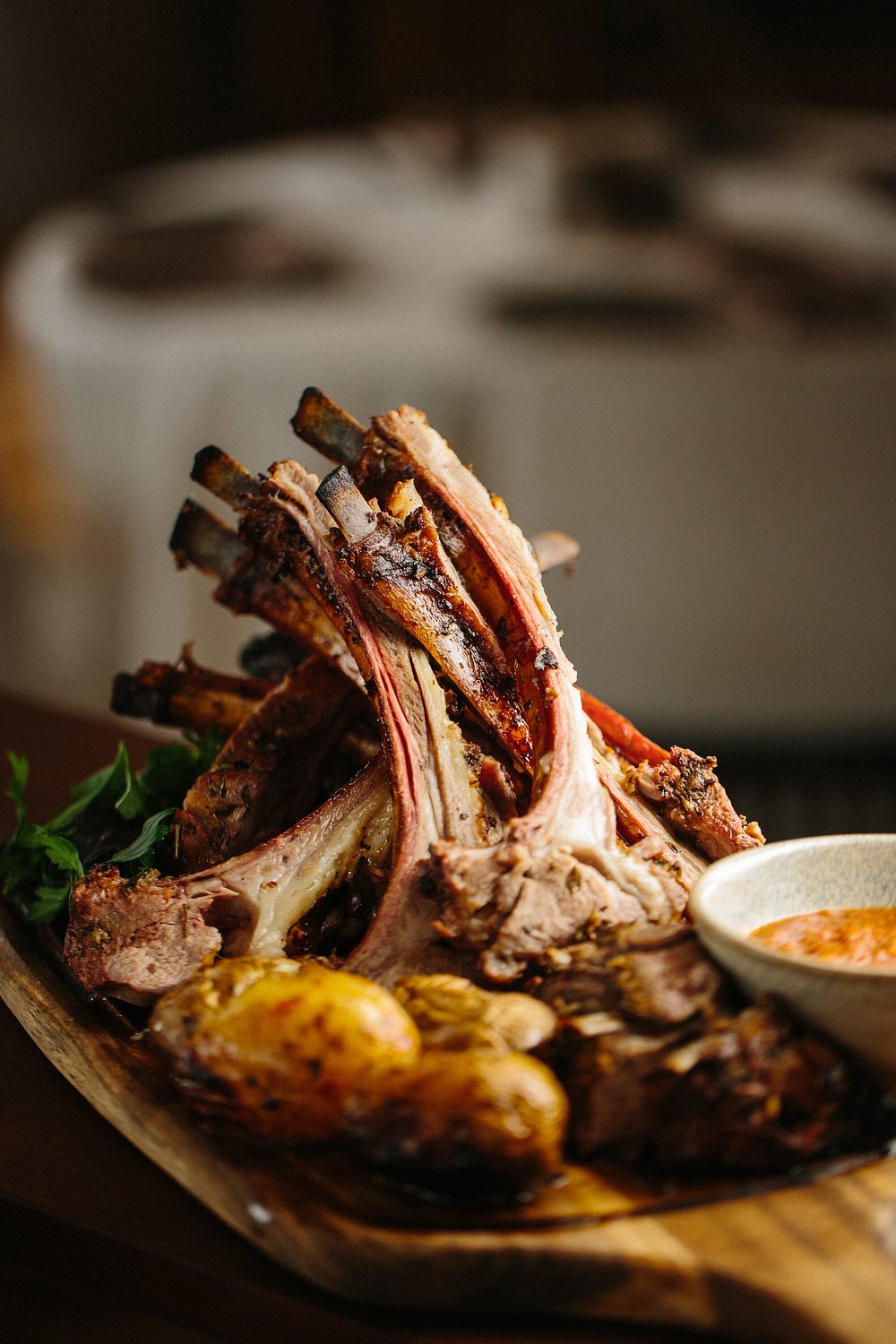 A roasted rack of lamb with young potatoes and sauce on a wooden board at Chayki in Baku