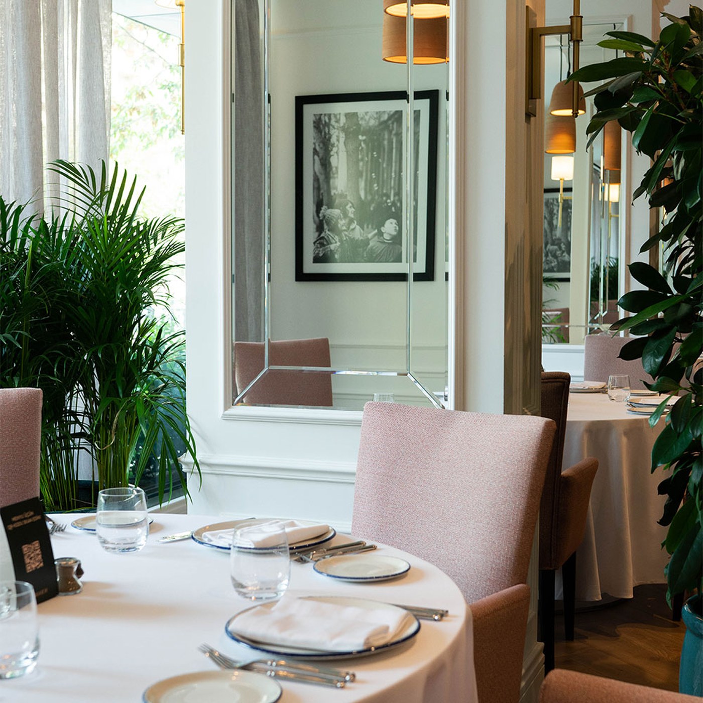 A bright, contemporary dining room in Baku with pale upholstery and tall windows