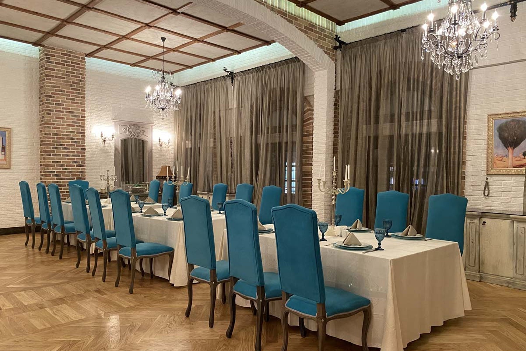An elegant private dining room with crystal chandeliers, brick columns and a long dressed table