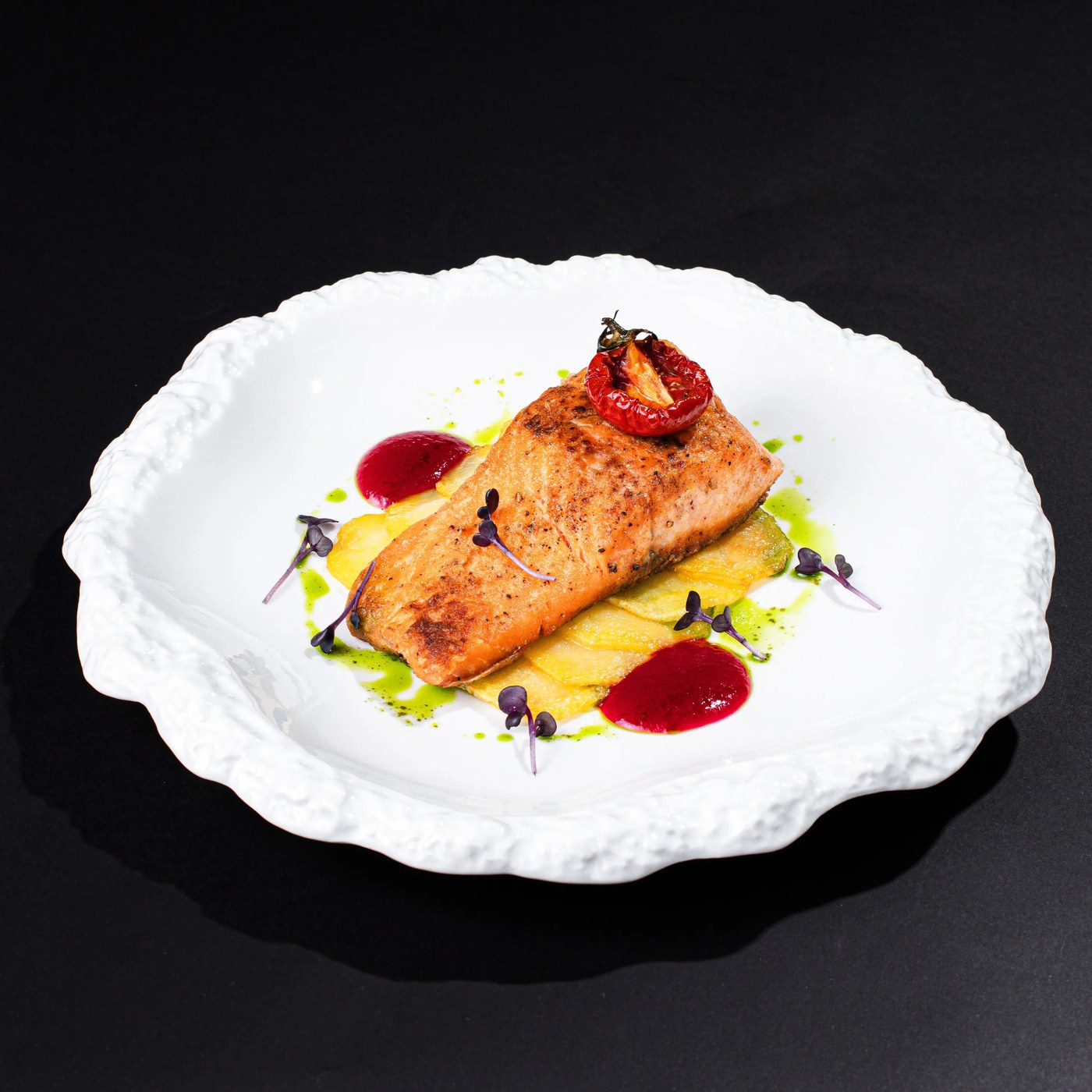 Wild-caught Caspian Osetra sturgeon fillet plated with confit tomato and herb oil on sculpted porcelain