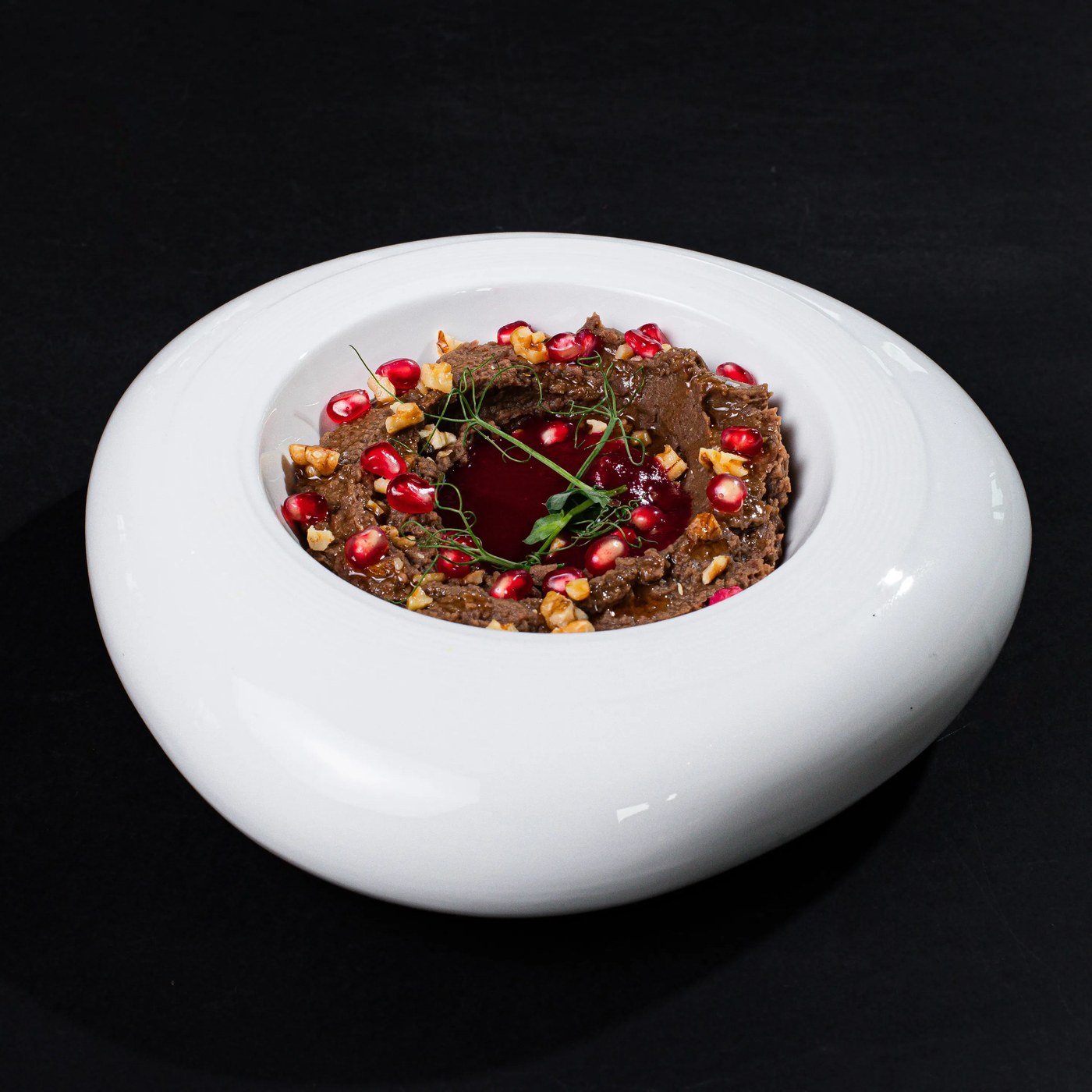 A regional grain and pomegranate dish plated in a curved white bowl