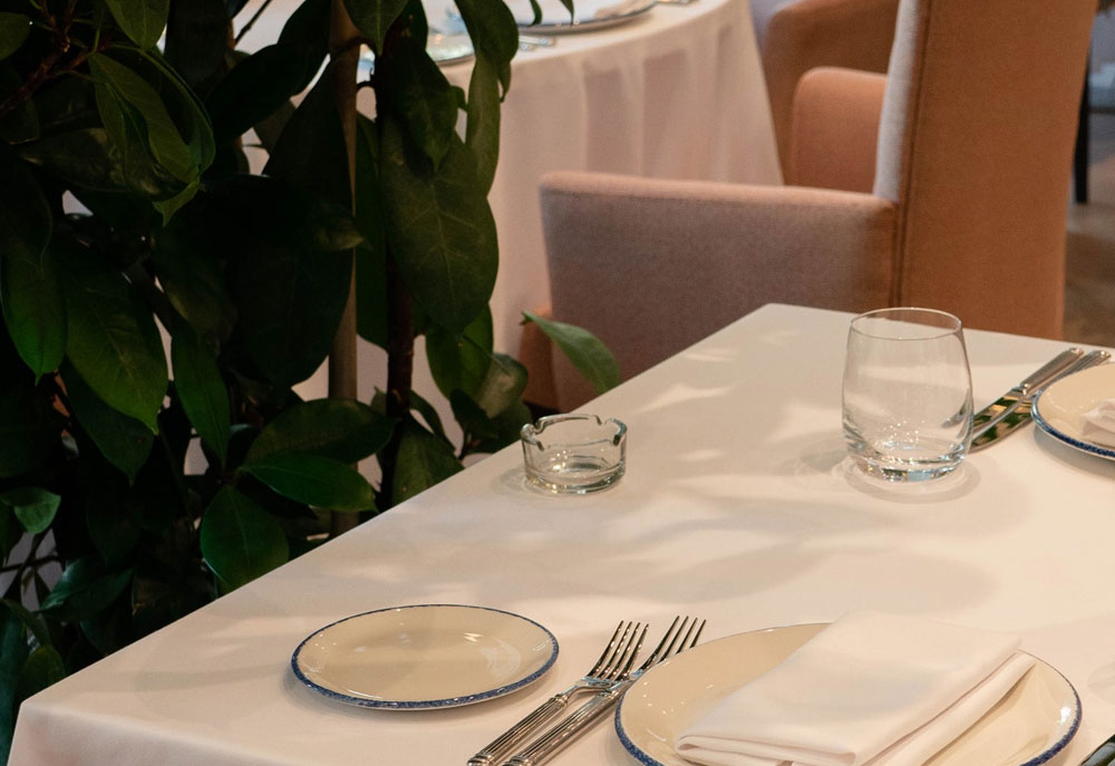 A close view of a table laid with linen, silver and glassware before service